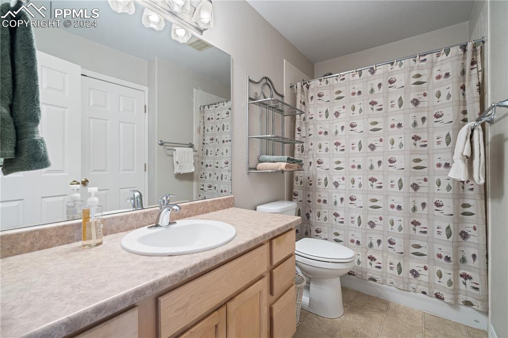 Image 31 of 49: Bathroom featuring tile patterned floors, a shower with curtain, toilet, an