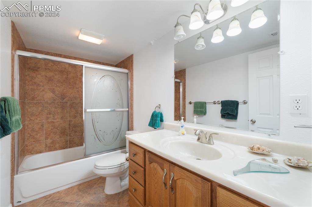 Image 34 of 49: Full bathroom with tile patterned flooring, vanity, toilet, and shower / ba