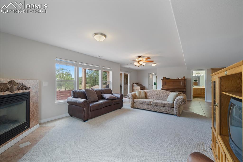 Image 40 of 49: Carpeted living room featuring ceiling fan and a high end fireplace