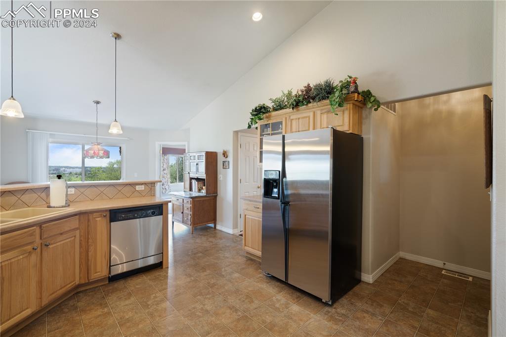 Image 5 of 49: Kitchen with hanging light fixtures, stainless steel appliances, high vault