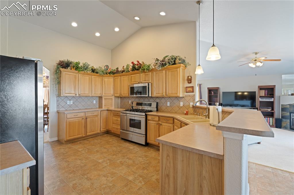 Image 7 of 49: Kitchen with tasteful backsplash, decorative light fixtures, kitchen penins
