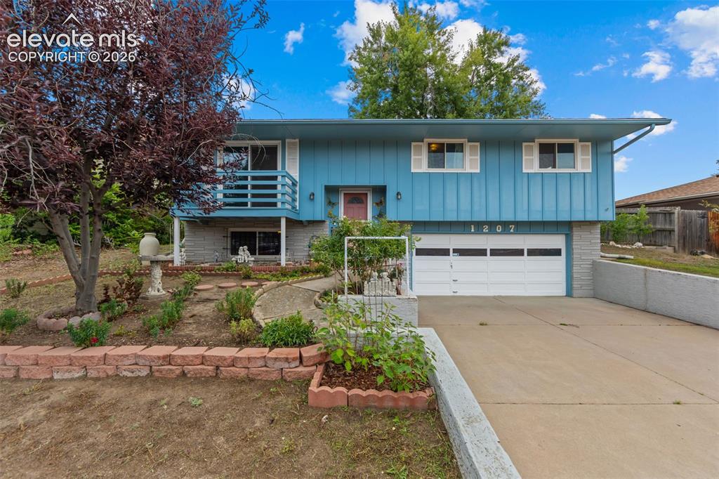 Caption: Bi-level residence featuring blue vertical siding, white window shutters, and a white garage door