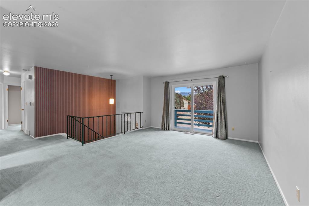 Image 10 of 35: Sliding glass door, light blue carpeting, horizontal wood panel accent wall