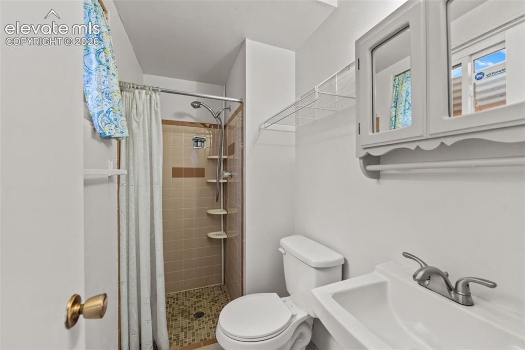 Image 15 of 35: Shower with tiled walls and floor, vanity with integrated sink, and wall-mo