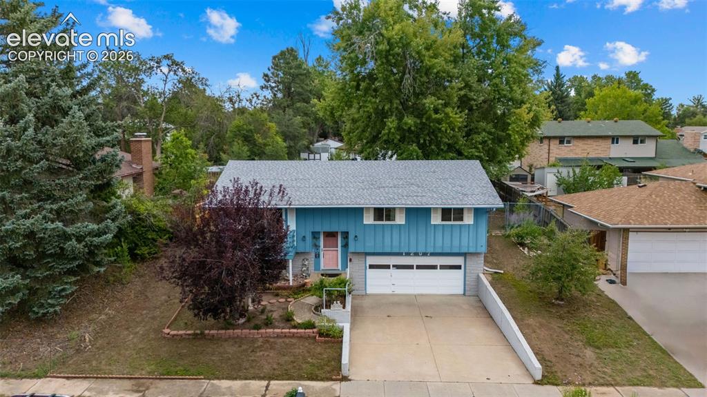 Image 24 of 35: Blue exterior siding with white trim, attached two-car garage, concrete dri