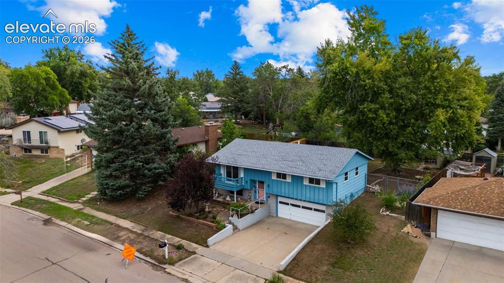 Image 25 of 35: Split-level residence featuring a two-car garage, established landscaping, 
