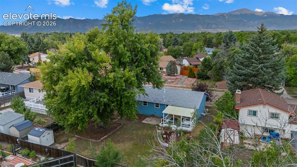 Image 30 of 35: Expansive backyard featuring a mature tree, two storage sheds, and a covere