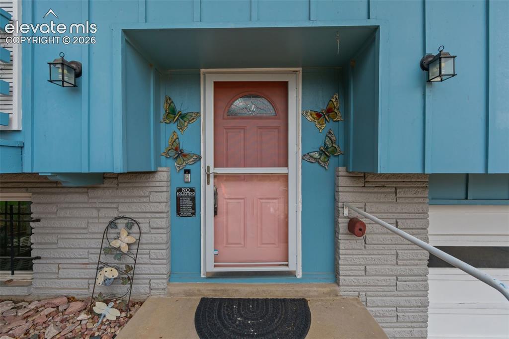Image 4 of 35: Recessed entry with two lantern-style wall sconces, wood paneling, and a st
