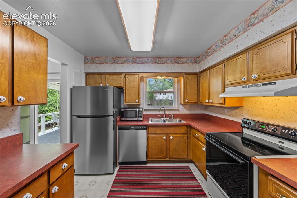 Image 7 of 35: Wood-finish cabinetry with white hardware, coordinating red countertops, an