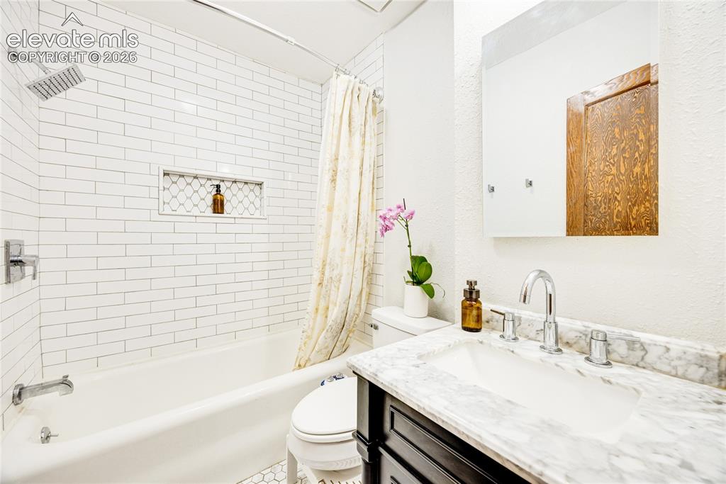 Image 16 of 33: Subway tile shower surround with a built-in niche, marble countertop, chrom