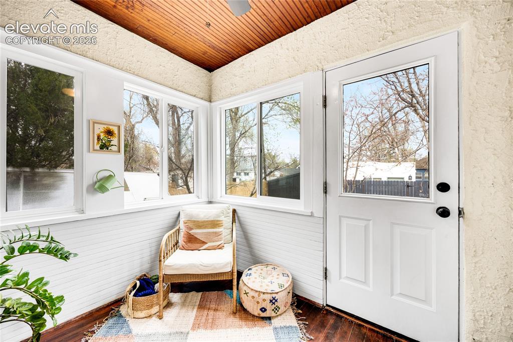 Image 20 of 33: Sunroom with wood-finish flooring, white paneled lower walls, and multiple