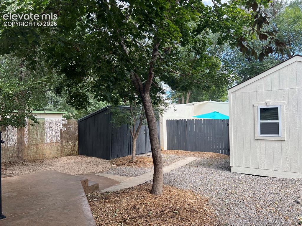 Image 22 of 33: Main House Yard with stamped concrete patio, pea gravel patoi, dark-stained