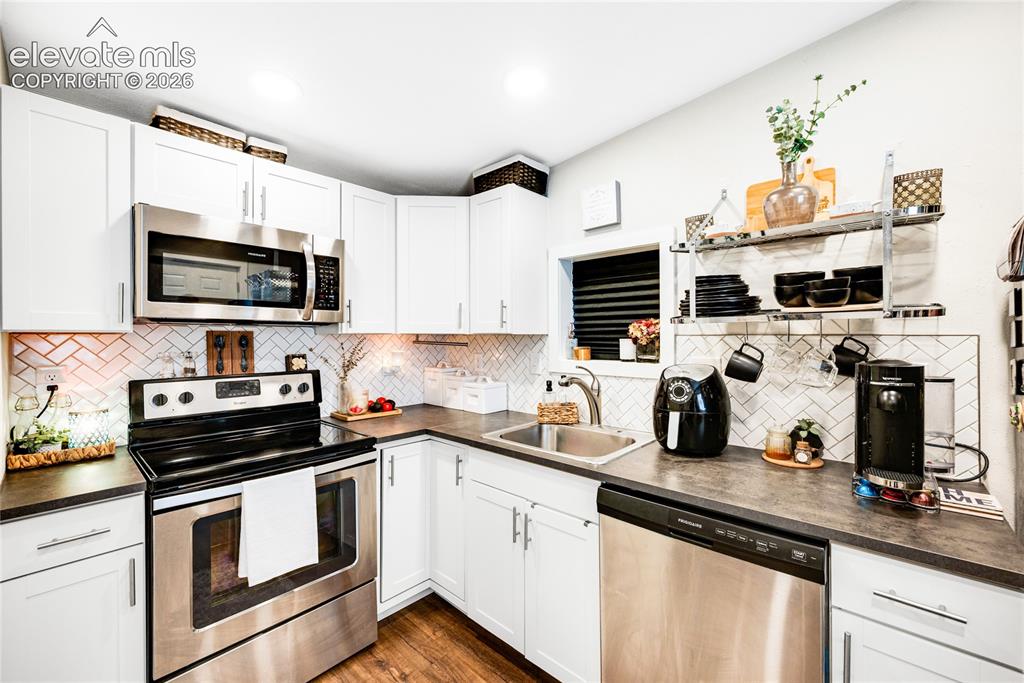 Image 27 of 33: ADU/Cottage - White shaker-style cabinetry with stainless steel appliances,