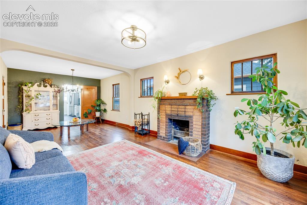 Image 4 of 33: Hardwood flooring, brick fireplace, wood-framed windows, and recessed arche