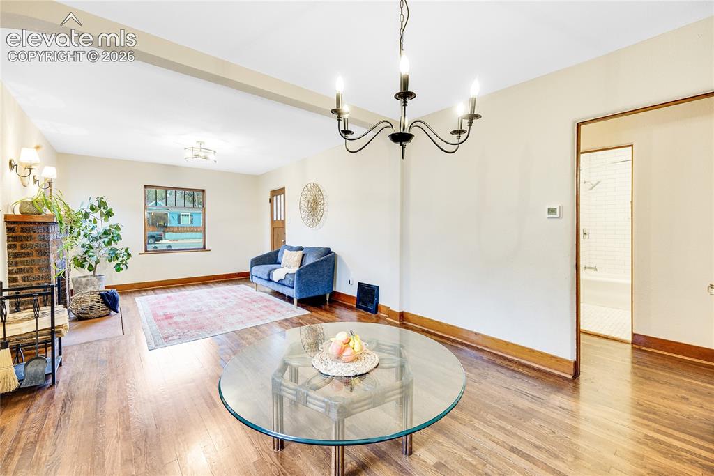 Image 6 of 33: Hardwood flooring, window with wood trim, and a classic chandelier
