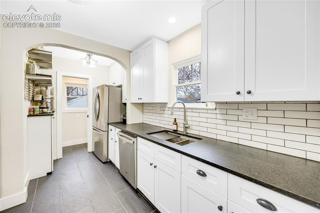 Image 7 of 33: Kitchen featuring white shaker cabinetry, stainless steel appliances, leath