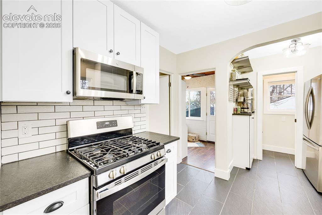 Image 8 of 33: Kitchen featuring white shaker cabinetry, stainless steel appliances, leath