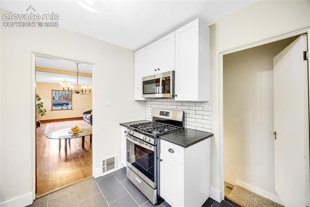 Image 9 of 33: Kitchen featuring white shaker cabinetry, stainless steel appliances, leath
