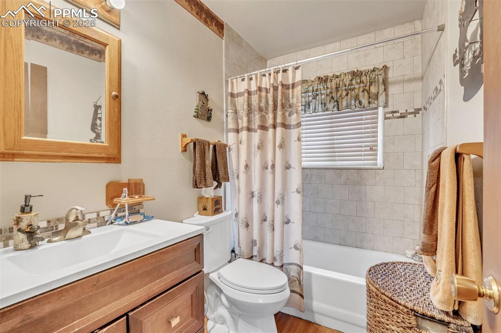 Image 18 of 49: Bathroom featuring vanity, shower / bath combo, and wood finished floors