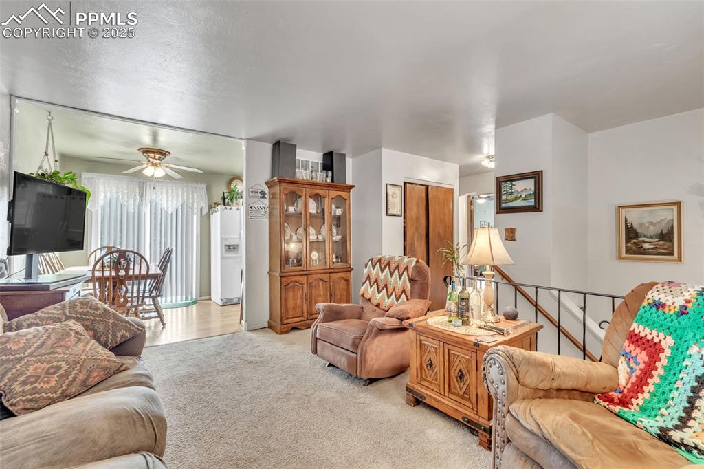 Image 34 of 49: Living room with light carpet and a ceiling fan