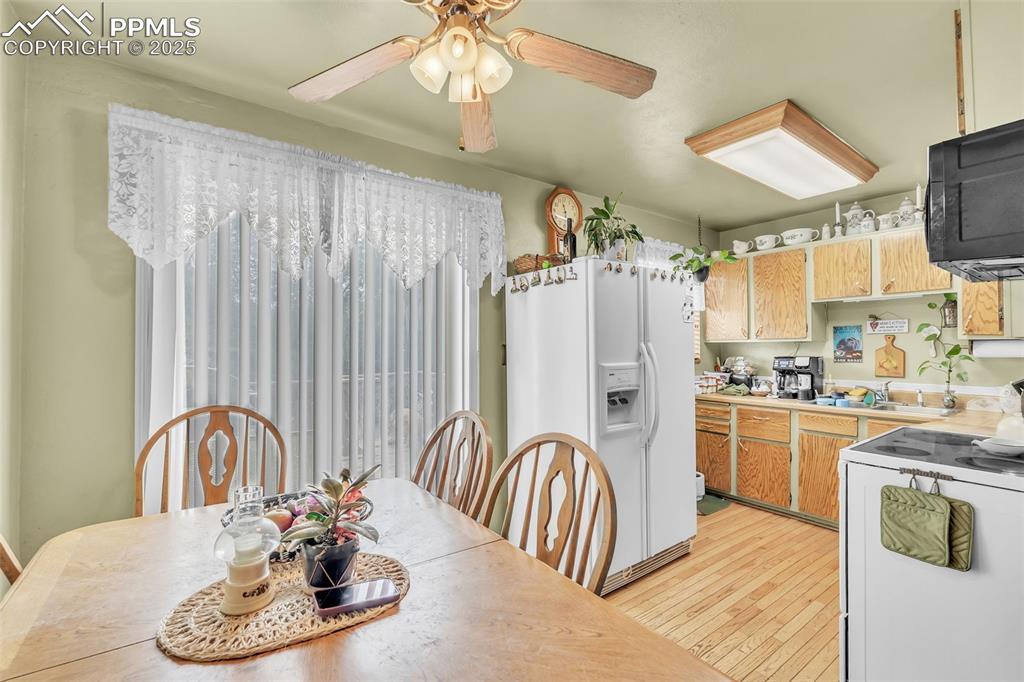 Image 35 of 49: Dining area with light wood-style floors and a ceiling fan
