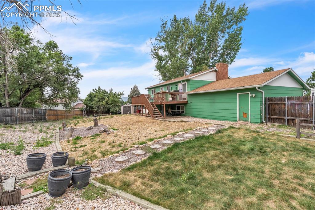 Image 38 of 49: Fenced backyard featuring stairway, a storage unit, and a wooden deck