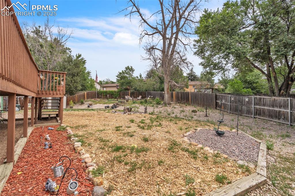 Image 41 of 49: Fenced backyard with stairs and a deck