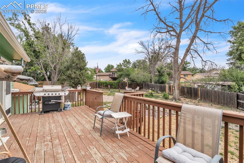 Image 43 of 49: Wooden terrace with a fenced backyard and a grill