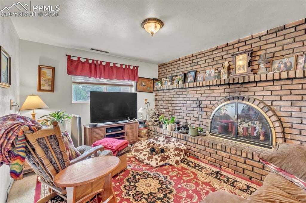 Image 9 of 49: Brick fireplace with mantel and hearth.