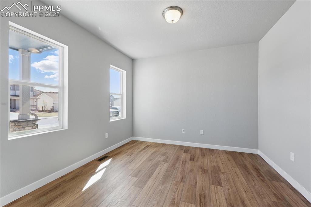 Image 11 of 36: Empty room with baseboards, visible vents, and wood finished floors