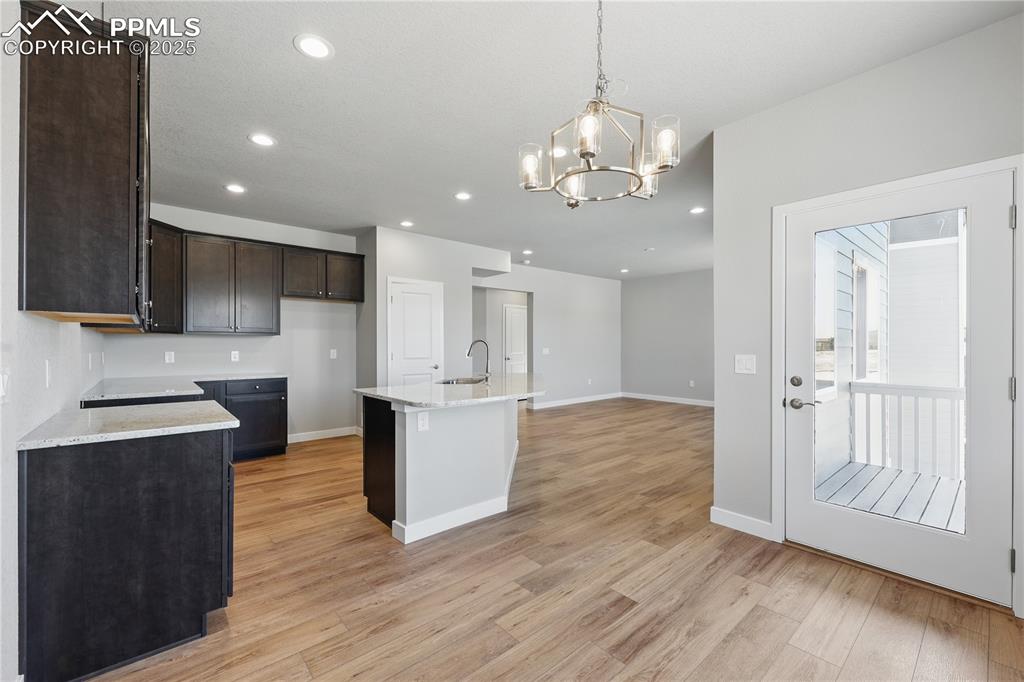 Image 17 of 36: Kitchen with recessed lighting, dark brown cabinetry, an inviting chandelie