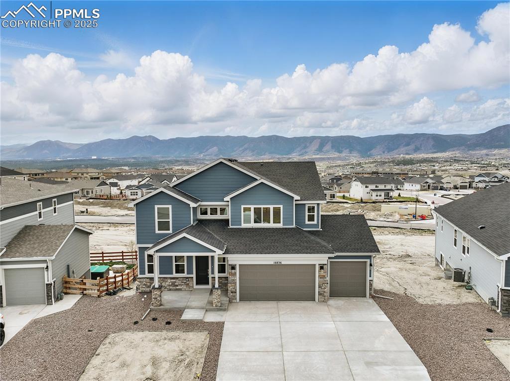 Image 2 of 36: Craftsman-style home featuring driveway, stone siding, a mountain view, an