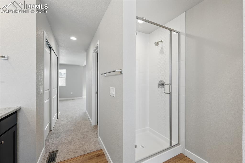 Image 24 of 36: Bathroom featuring visible vents, a stall shower, baseboards, wood finished
