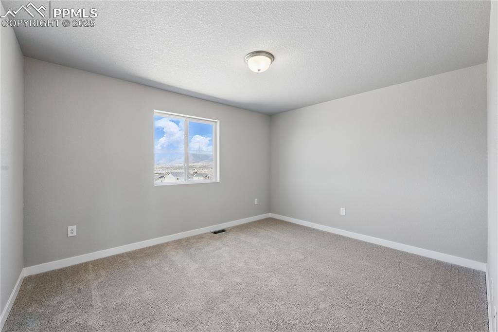 Image 26 of 36: Carpeted spare room with a textured ceiling, visible vents, and baseboards