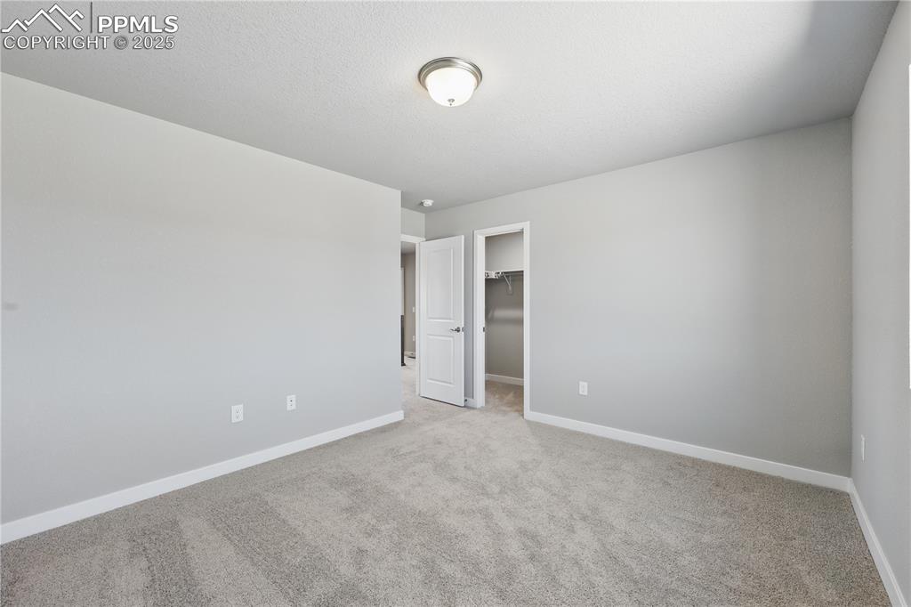 Image 27 of 36: Unfurnished bedroom featuring baseboards, a spacious closet, and light colo