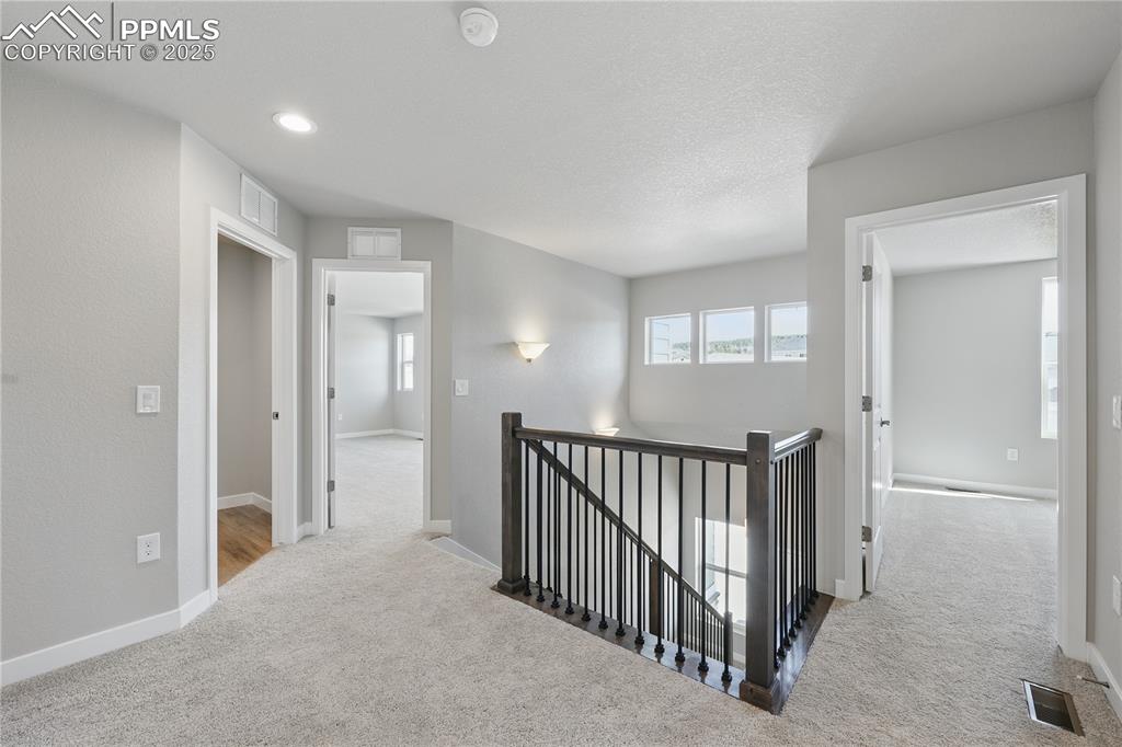 Image 28 of 36: Hallway featuring baseboards, visible vents, an upstairs landing, and carpe