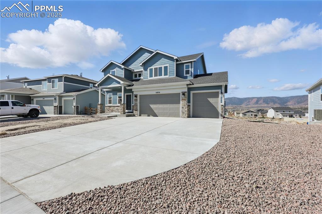 Image 8 of 36: View of front of property featuring concrete driveway, stone siding, an att