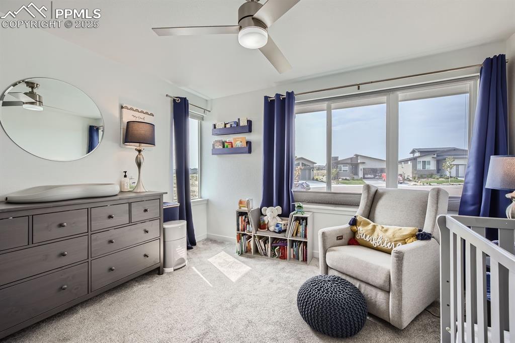 Image 16 of 31: Bedroom with light carpet, a nursery area, and ceiling fan