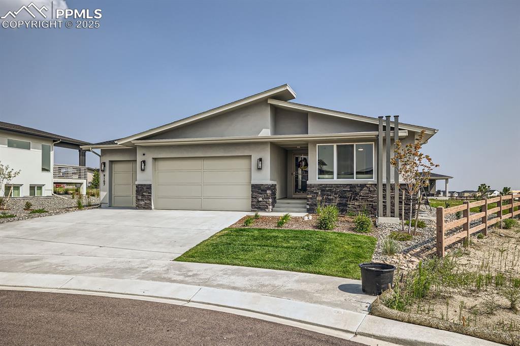 Image 2 of 31: View of front of property with an attached garage, stucco siding, stone sid