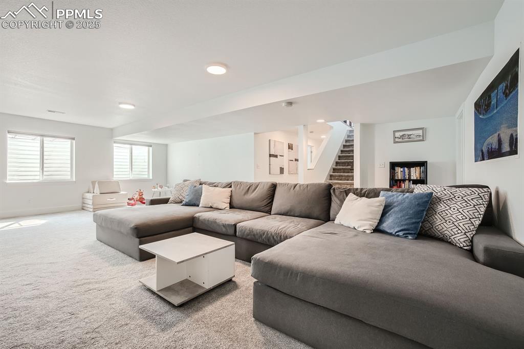 Image 21 of 31: Living area with carpet flooring, stairway, and recessed lighting
