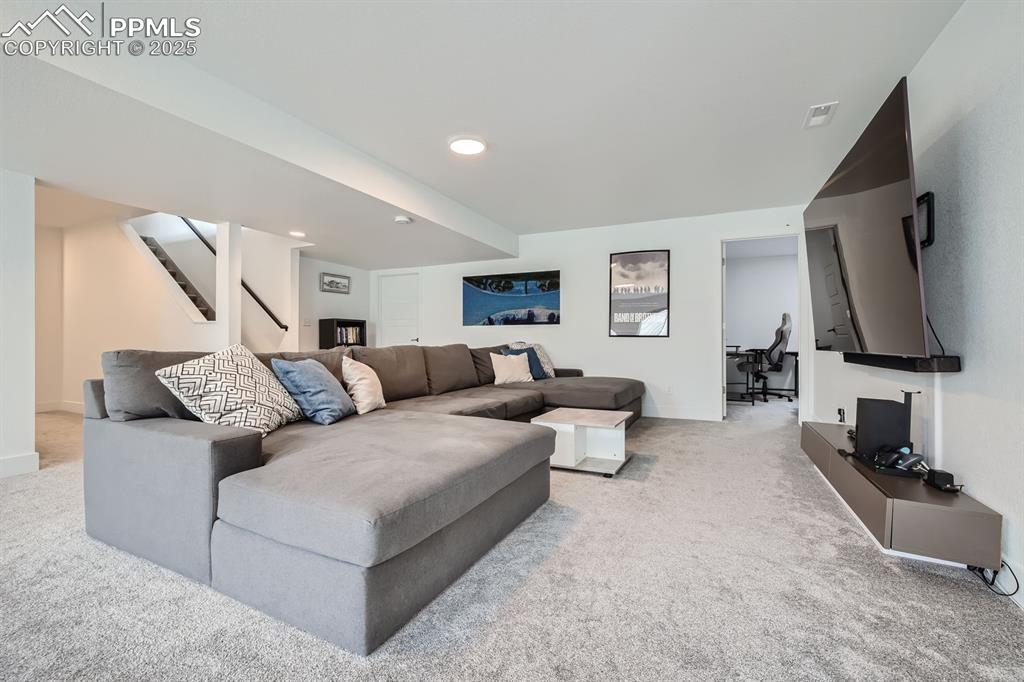 Image 22 of 31: Living area featuring light carpet, stairway, and recessed lighting