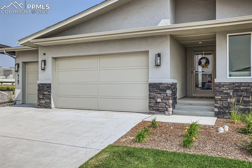 Image 3 of 31: View of front of property with stone siding, stucco siding, and driveway