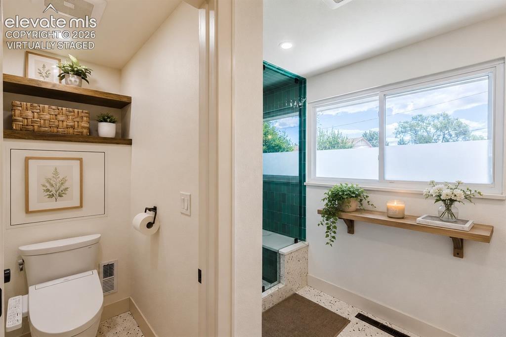 Image 15 of 49: Bathroom featuring a glass-enclosed shower with green tile, a window with f