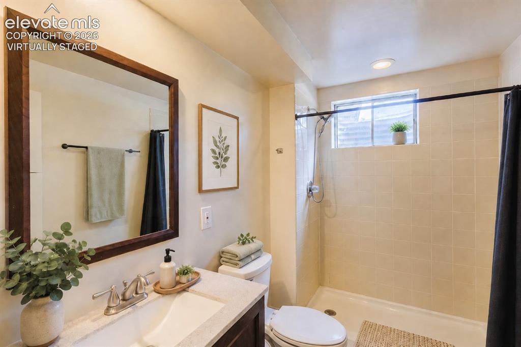 Image 18 of 49: Bathroom featuring a dark wood-framed mirror, vanity with a light-toned cou