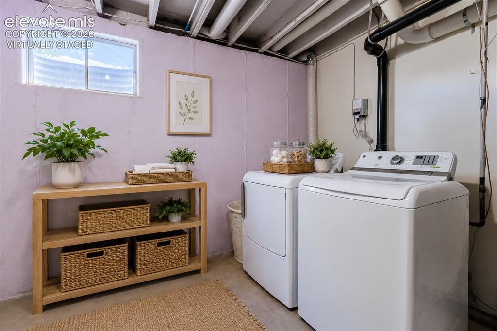 Image 25 of 49: Dedicated laundry area featuring a washer and dryer, exposed ceiling joists