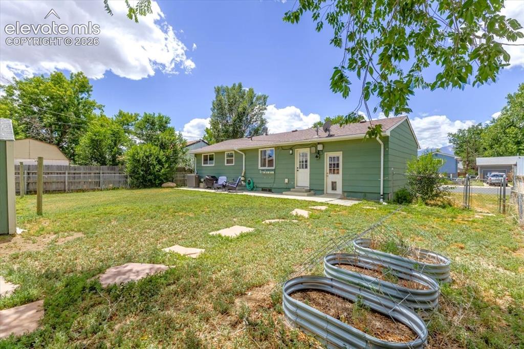 Image 27 of 49: Expansive backyard featuring a lush lawn, privacy fencing, and two raised g