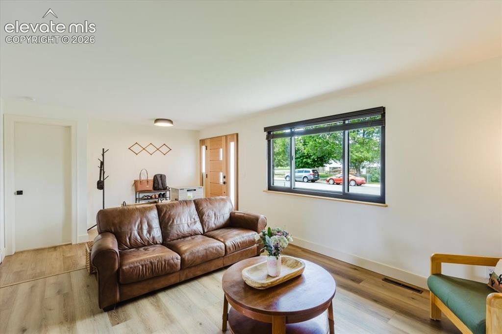 Image 31 of 49: Living area featuring wood-finish flooring, a contemporary window with dark