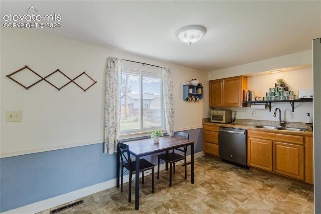 Image 33 of 49: Kitchen featuring wood cabinetry, a stainless steel dishwasher, and a doubl