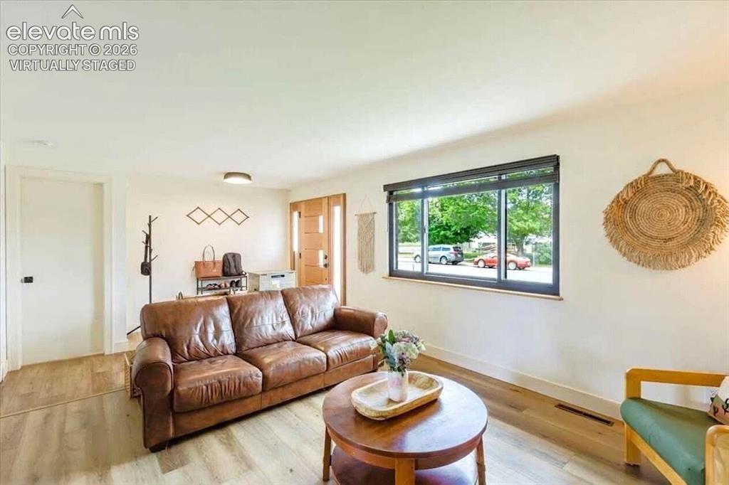 Image 4 of 49: Spacious living area featuring light wood-finish flooring, white walls, and