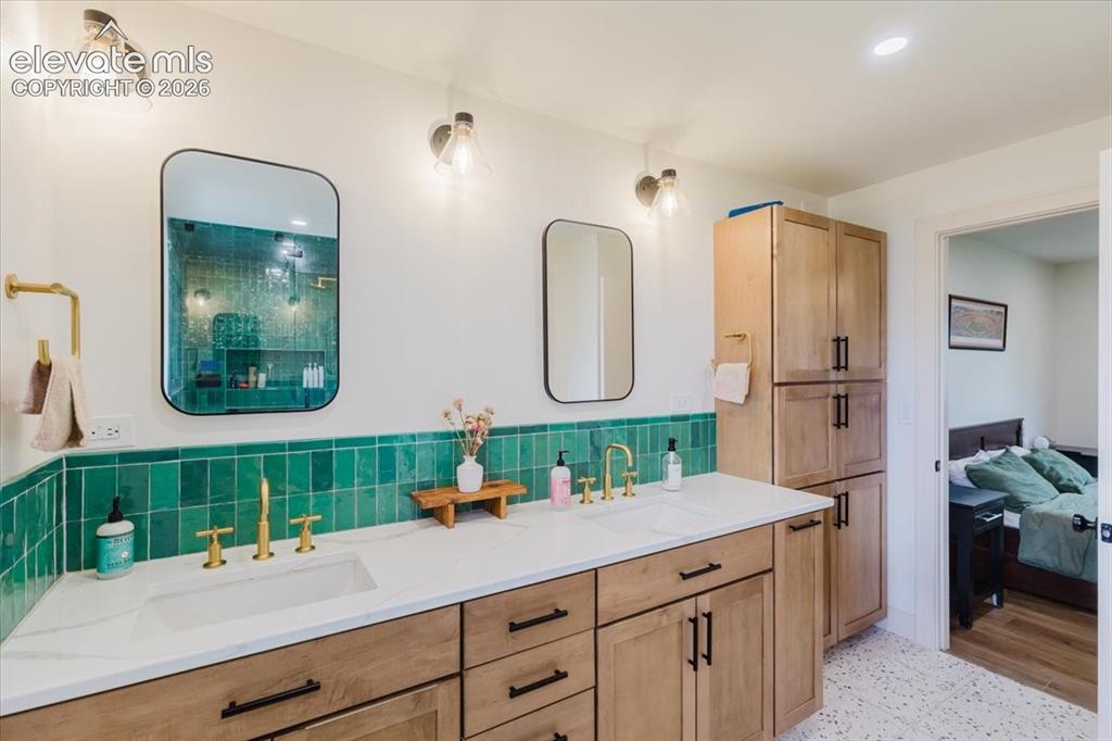 Image 40 of 49: Double vanity with light wood cabinetry, quartz-finish countertop, and brus